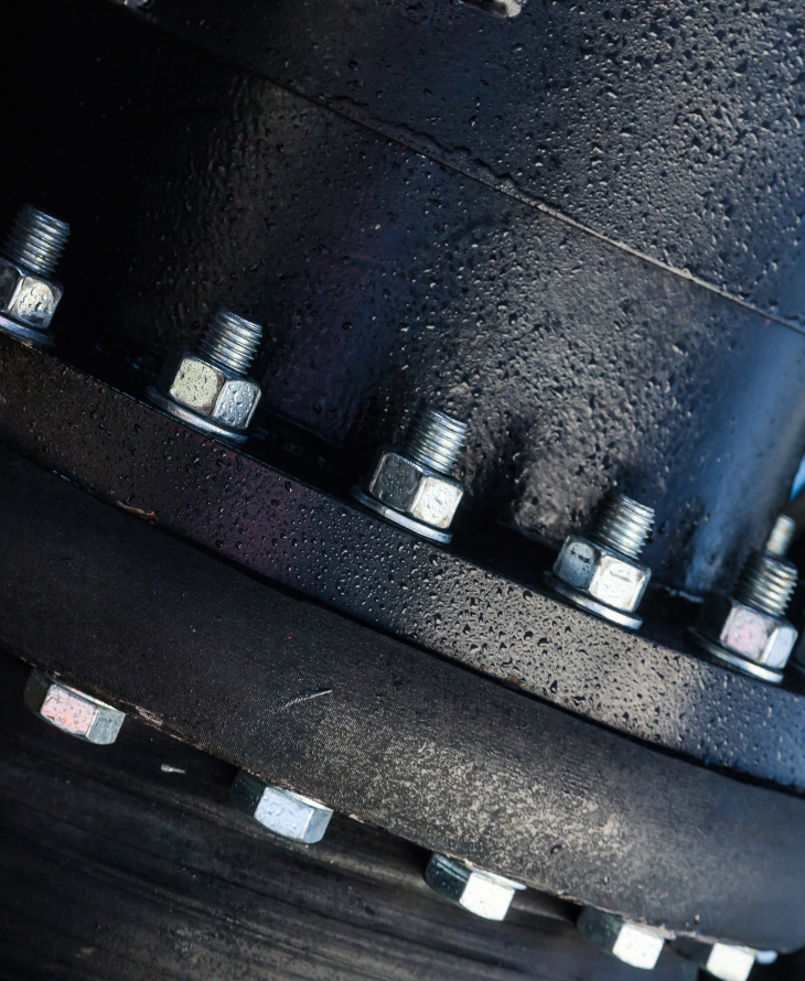 Cillindrical metal piece with nuts and bolts around it.