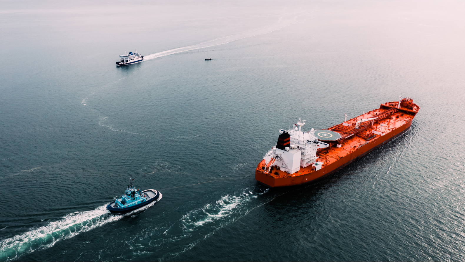 A ship breaking through a vast ice sheet in a polar region under a clear blue sky.