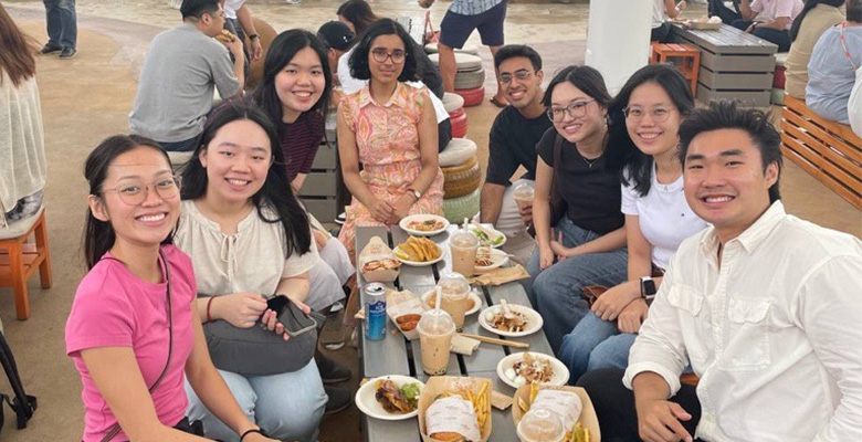 Group of colleagues enjoying food and drinks while socializing during a firm day.