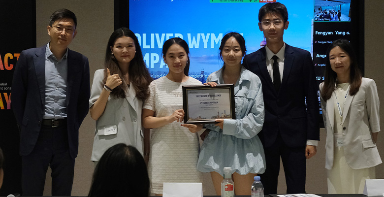 Colleagues holding a certificate of excellence at an Oliver Wyman case competition event.