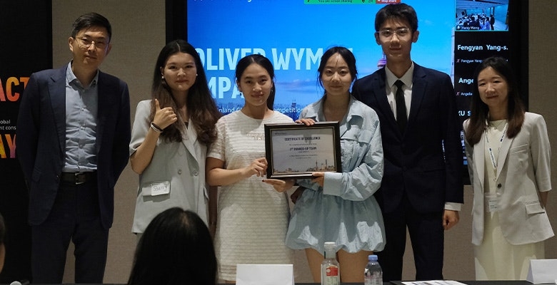 Colleagues holding a certificate of excellence at an Oliver Wyman case competition event.