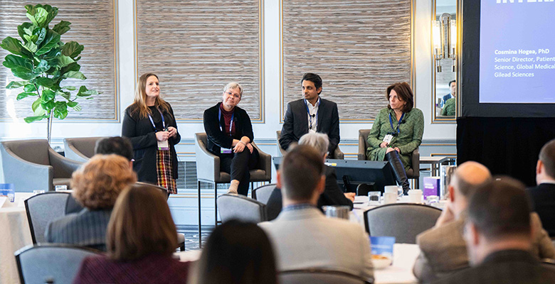 Photography of four professionals giving a presentation in a large room.