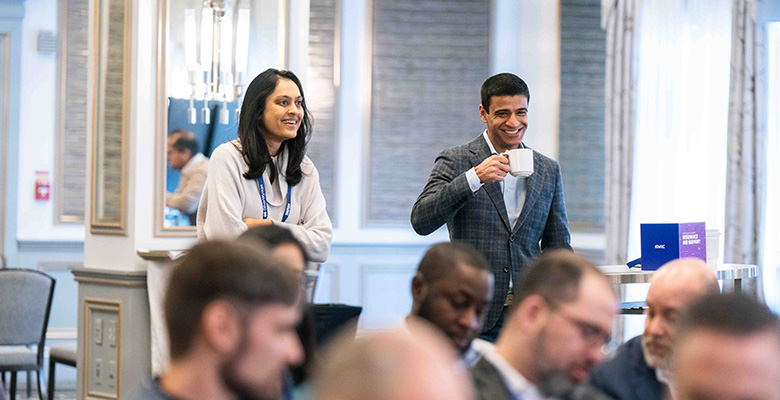 Photography of a woman and a man smiling while attending a conference.