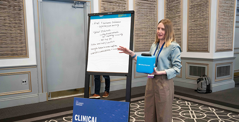 Photography of a woman presenting a clinical topic on a flip chart board.