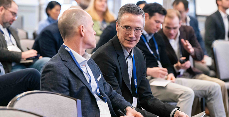 Photography of two men talking to each other while attending a conference.
