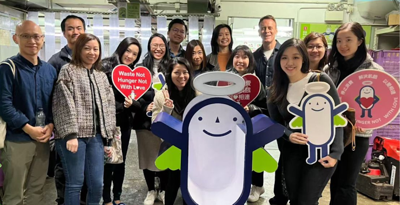 A group is gathered in a food redistribution center, holding signs promoting food relief initiatives, representing efforts to alleviate hunger and food waste.