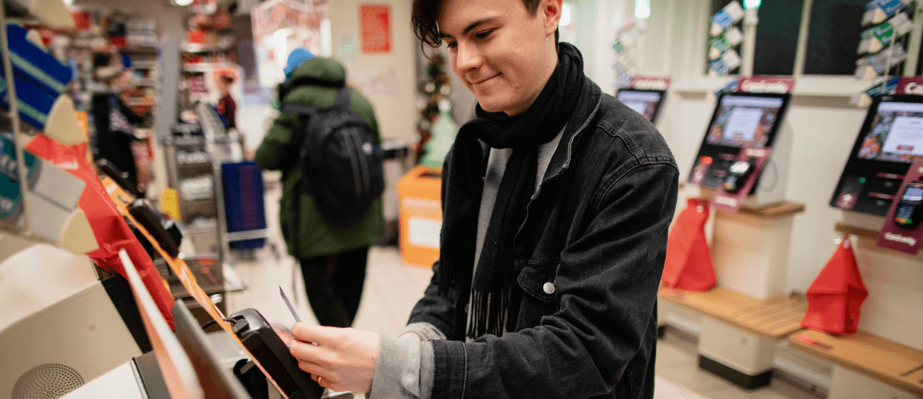 Young man uses a self checkout at a store