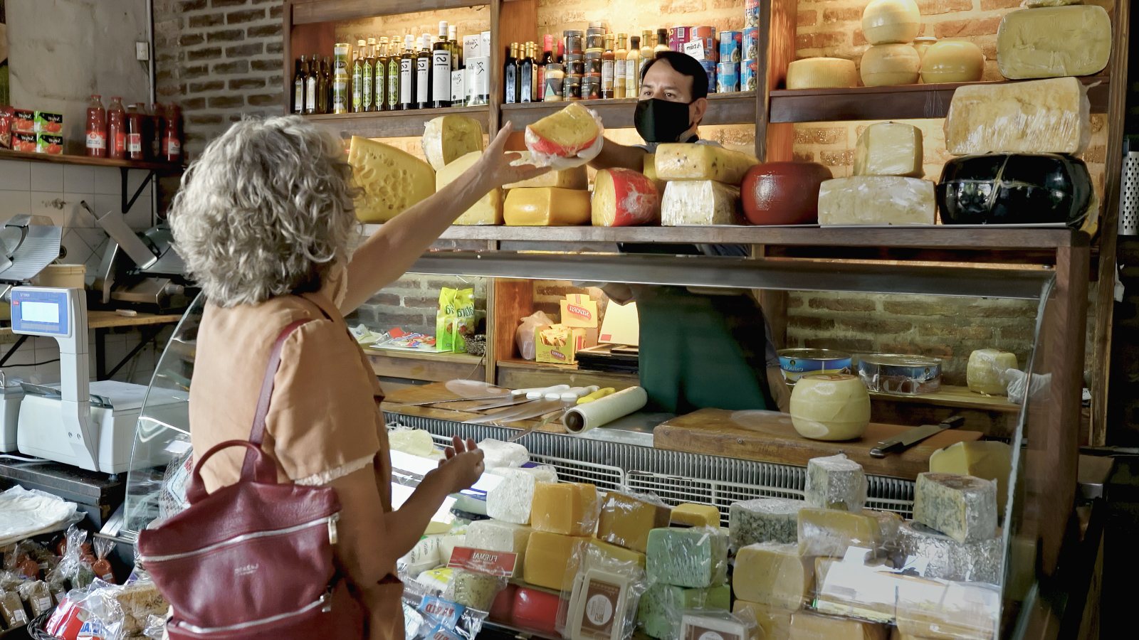 Woman picking up cheese from a local shop