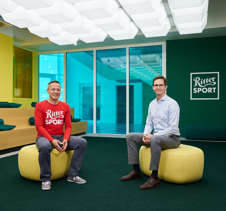 Close-up of two Ritter Sport chocolate bar wrappers, showcasing vibrant designs and the brand logo prominently displayed.