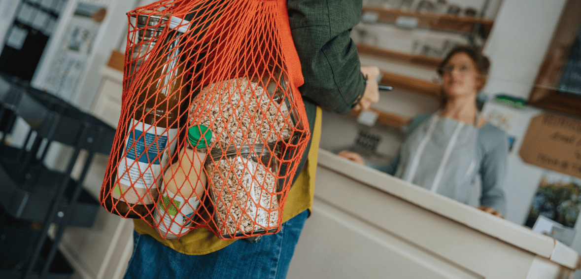 Person approches with a grocery bag a shop counter