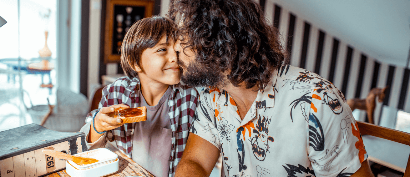 Father kisses his son during a breakfast at home