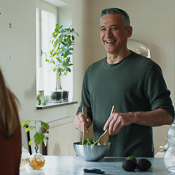 Laughing man mixing salad