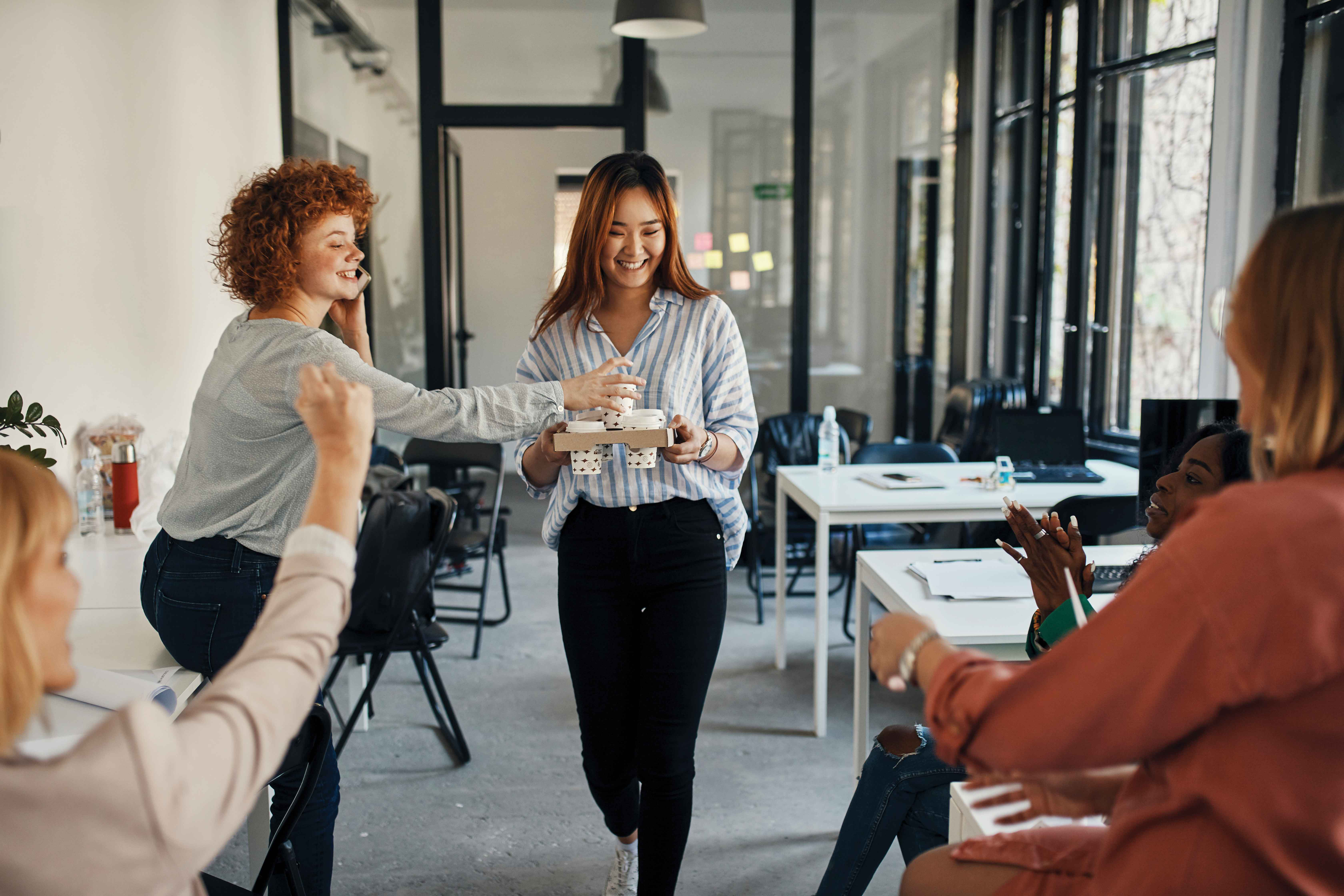 Picture that shows women in an office grabbing coffee from a coworkers hands